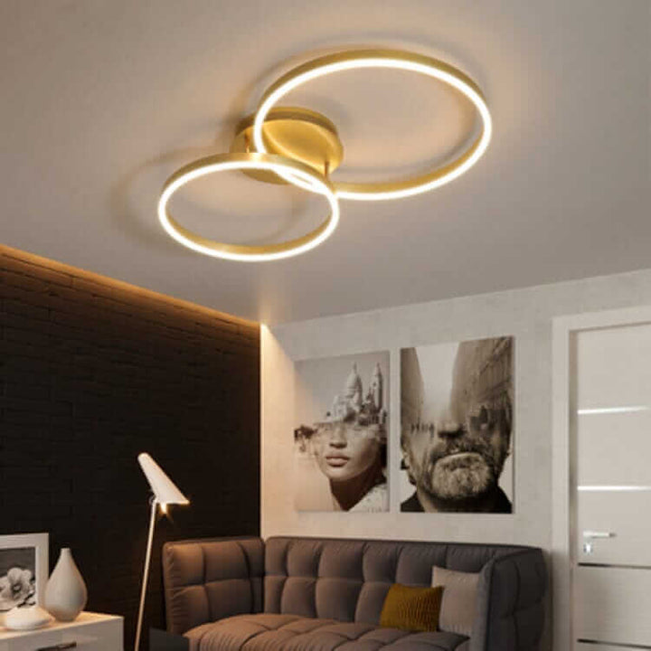 Modern LED chandelier with double circular rings illuminating a stylish living room.