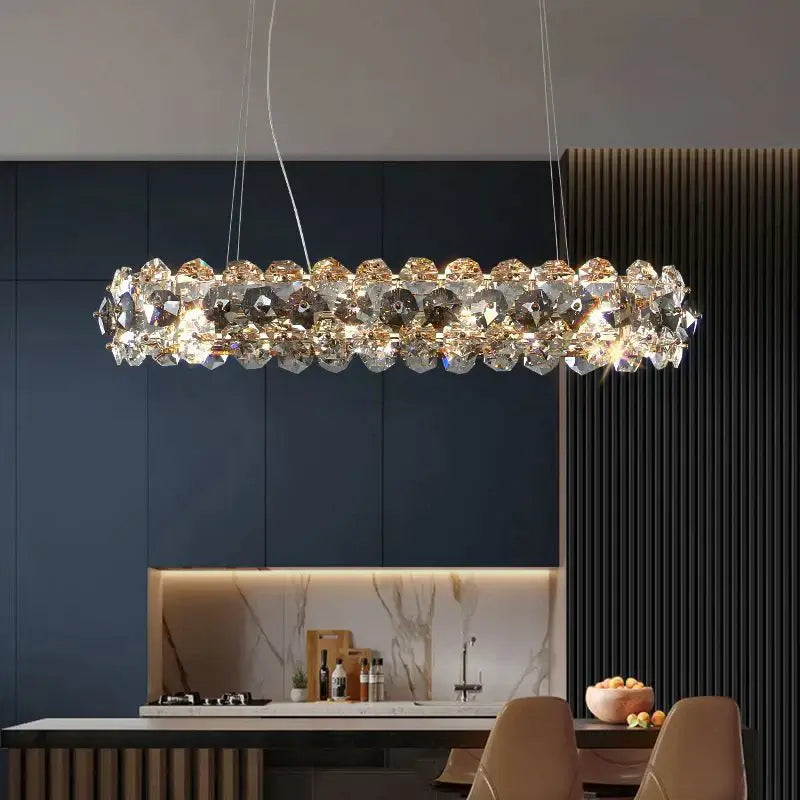 Elegant entryway chandelier featuring crystal accents, illuminating a modern kitchen with luxury ambiance.