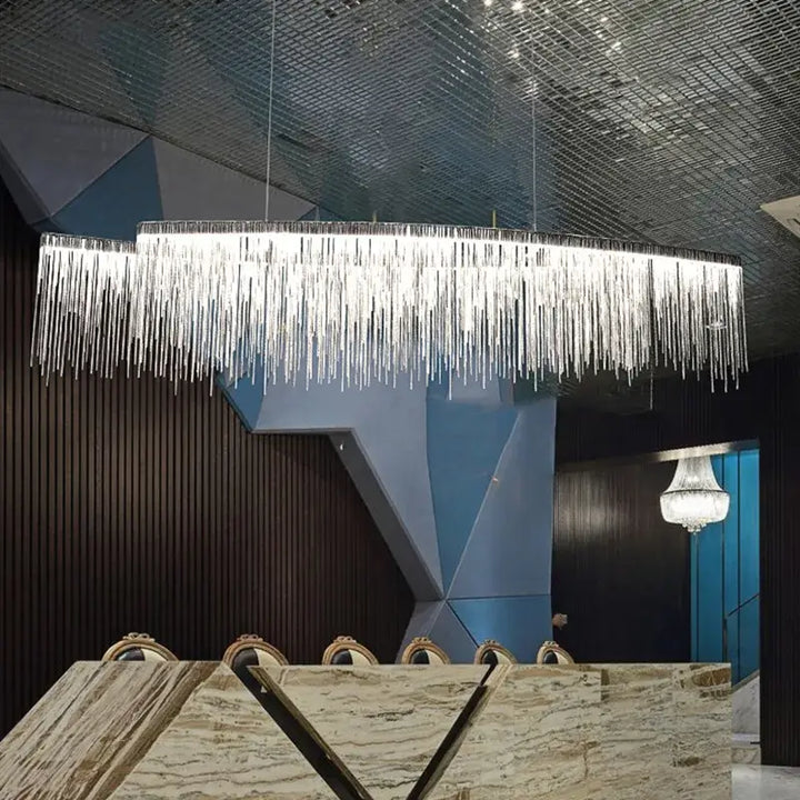 Linear chandelier with long tassel design, illuminating a modern dining area with elegance.