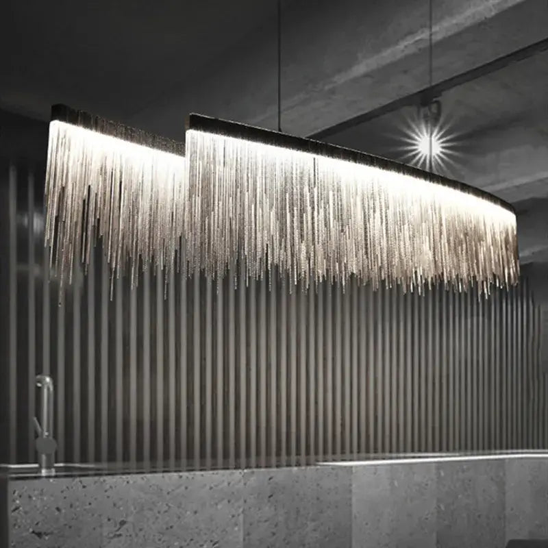 Linear chandelier with long tassels illuminating a modern dining room, featuring sleek design and warm glow.