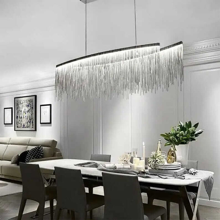 Elegant linear chandelier with tassels illuminating a stylish dining room table and modern decor.