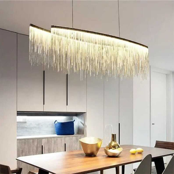 Luxury linear chandelier with long tassels over a modern dining table, enhancing room aesthetics with warm light.