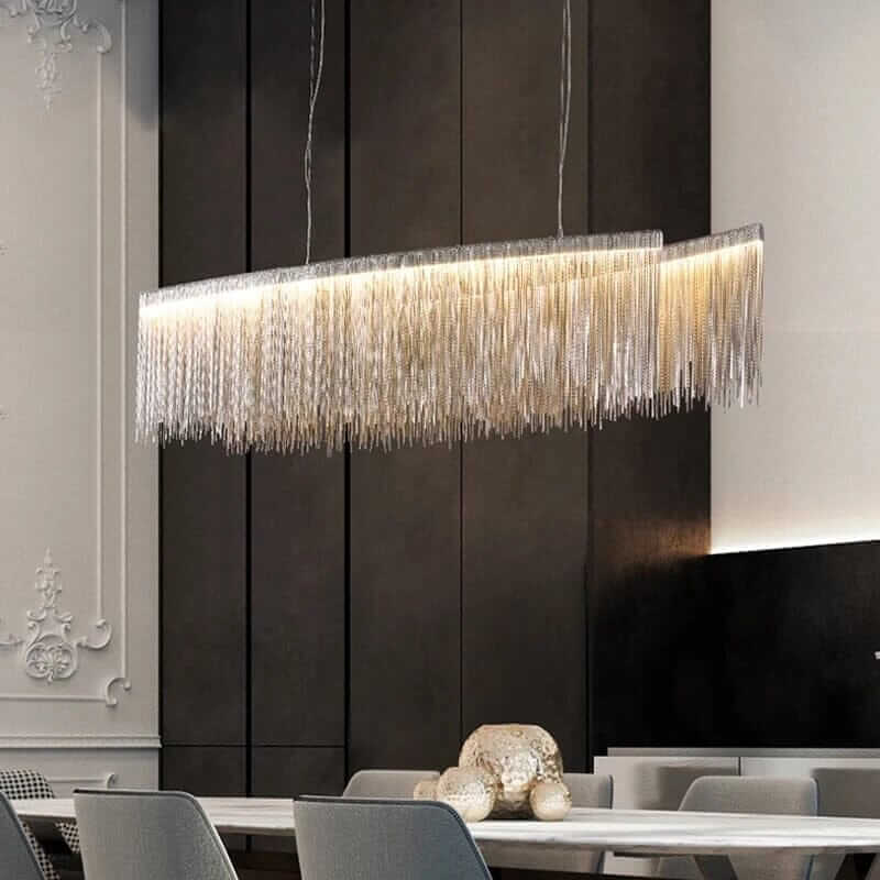 Linear chandelier with long tassels illuminating a modern dining room, enhancing elegance and warmth.