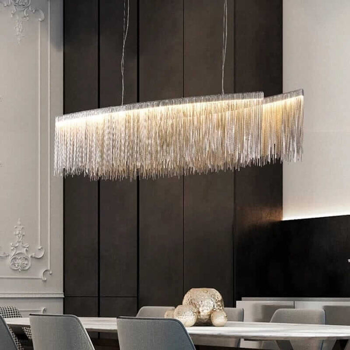Linear chandelier with long tassels illuminating a modern dining room, enhancing elegance and warmth.