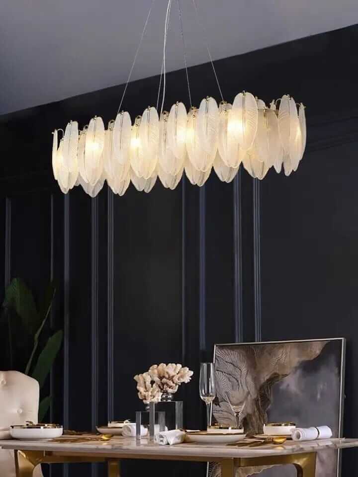 Stylish entryway chandelier with leaf-like design illuminating a modern dining table.