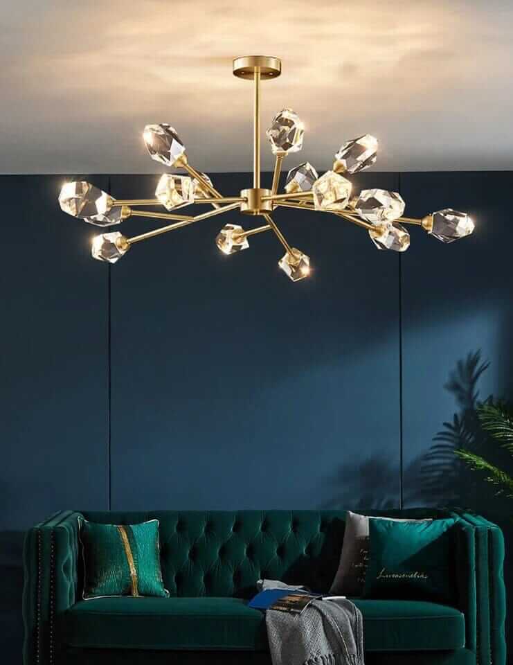 Gold Sputnik chandelier with crystal accents illuminating a stylish living space with a green velvet sofa.