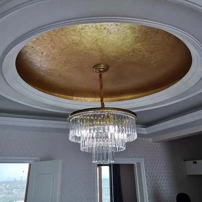 Elegant round golden crystal chandelier hanging from a decorative ceiling with a gold accent.