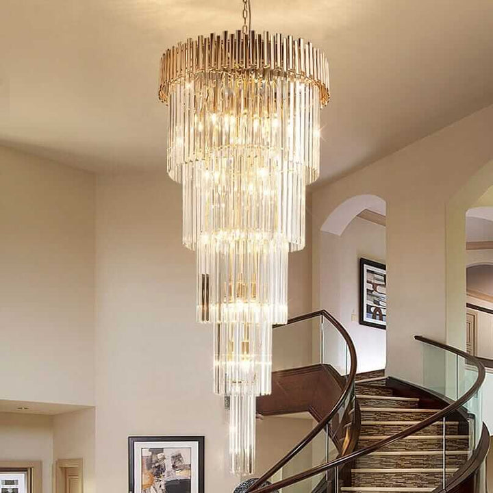 Gold chandelier with cascading crystal design illuminating a staircase in a contemporary interior.