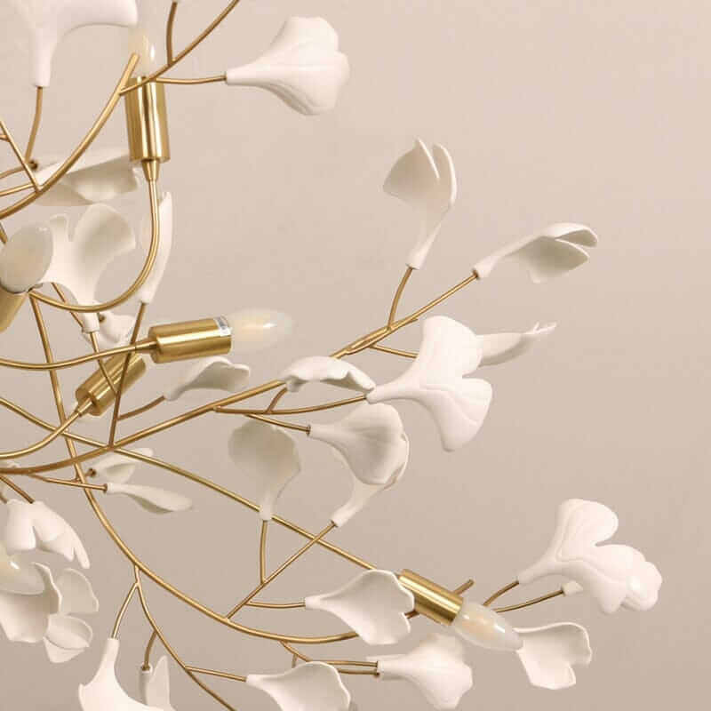 Floral chandelier with white petals and gold frame, creating a soft, inviting glow for home decor ambiance.