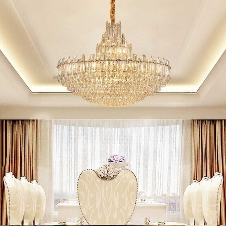 Elegant foyer chandelier with gold-plated brass and crystal accents illuminating a stylish dining room.