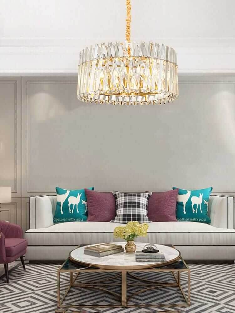 Luxury crystal LED lamp hanging above a stylish couch in a modern living room with decorative pillows.