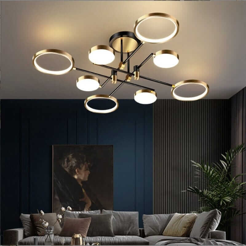 Elegant black and gold chandelier with circular lights, enhancing a modern cozy living room atmosphere.