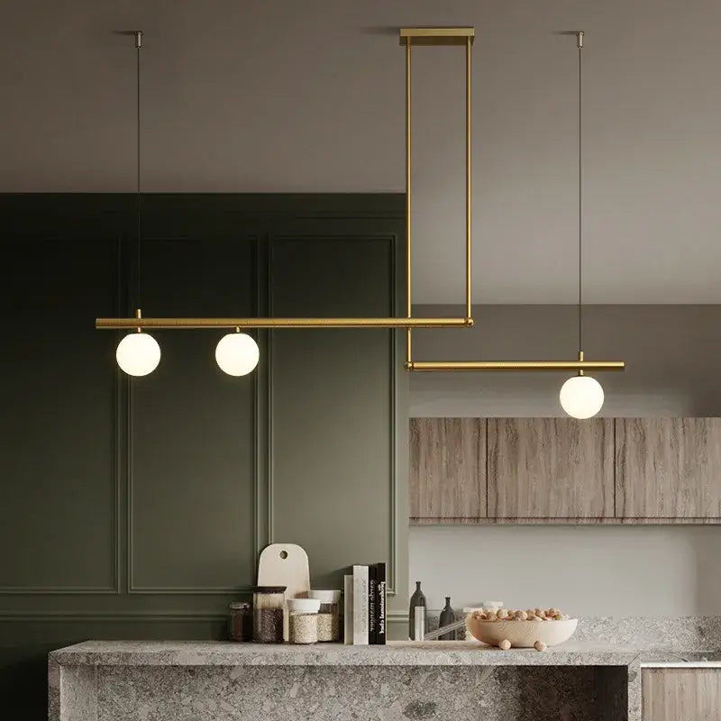 Black and gold chandelier hanging over a kitchen island, showcasing modern design with frosted globes for cozy lighting.