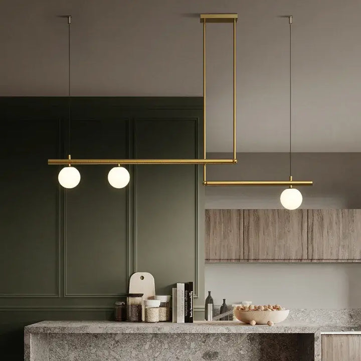 Black and gold chandelier hanging over a kitchen island, showcasing modern design with frosted globes for cozy lighting.
