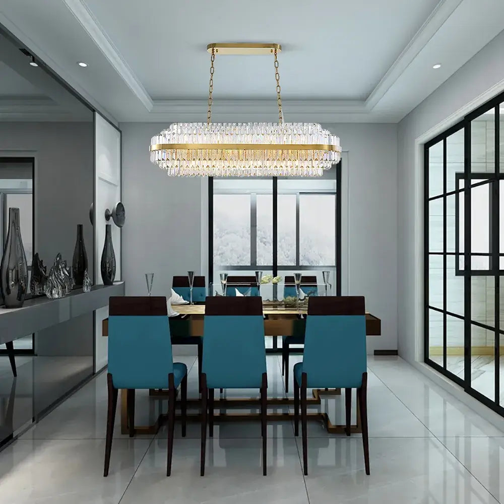 Elegant gold chandelier illuminating a modern dining room with stylish teal chairs and large windows.