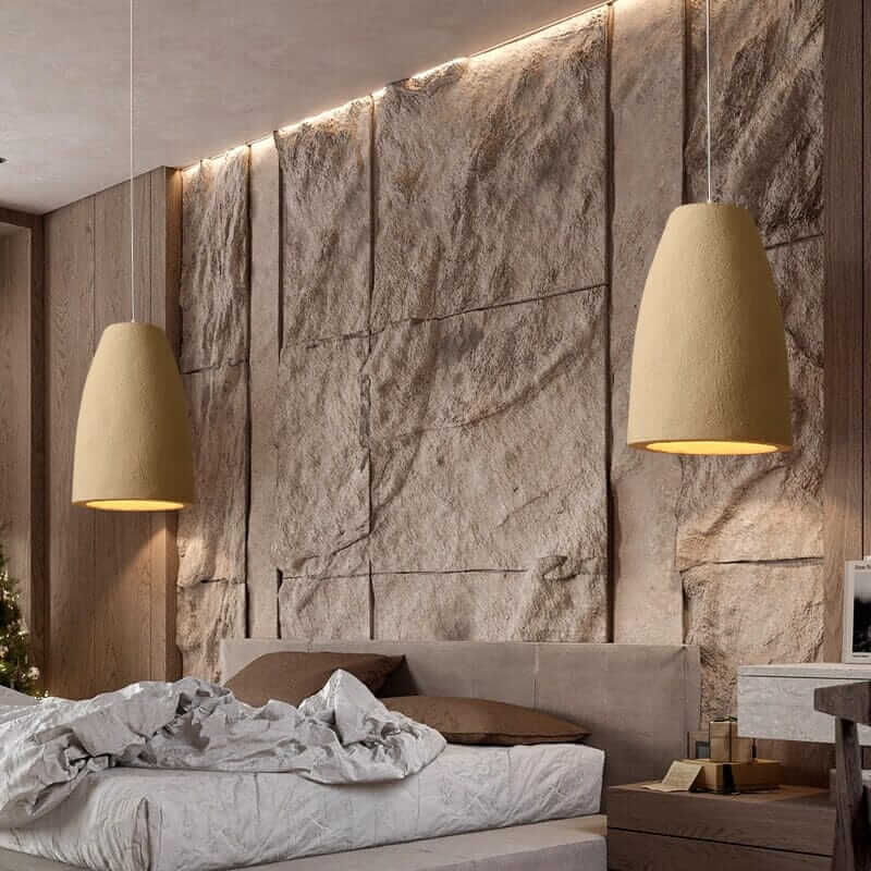 Wabi Sabi Pendant Light illuminating a modern bedroom with textured stone wall and stylish bedding.