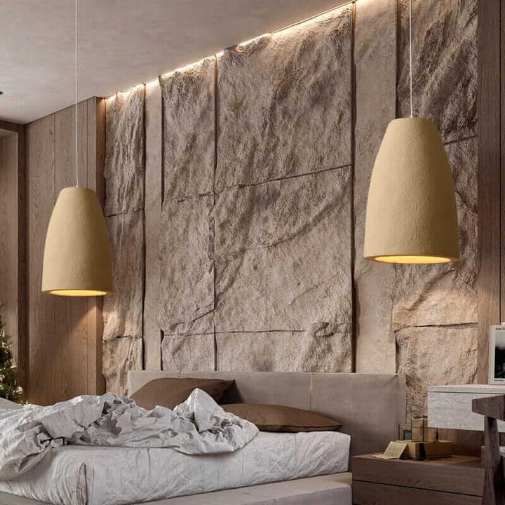 Wabi Sabi Pendant Light illuminating a modern bedroom with textured stone wall and stylish bedding.