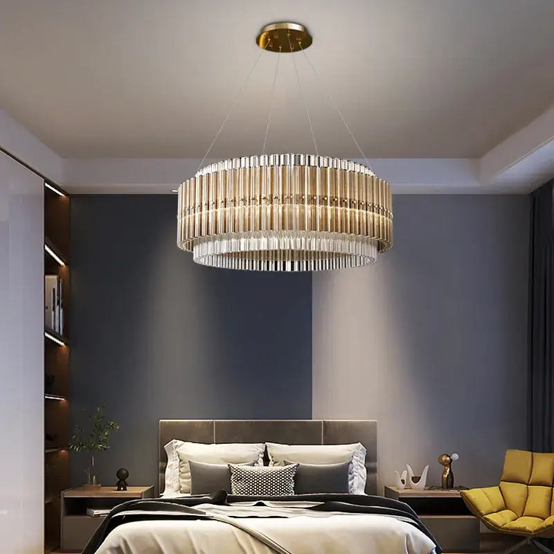 Elegant round gold chandelier illuminating a modern bedroom with stylish furniture and soft lighting.