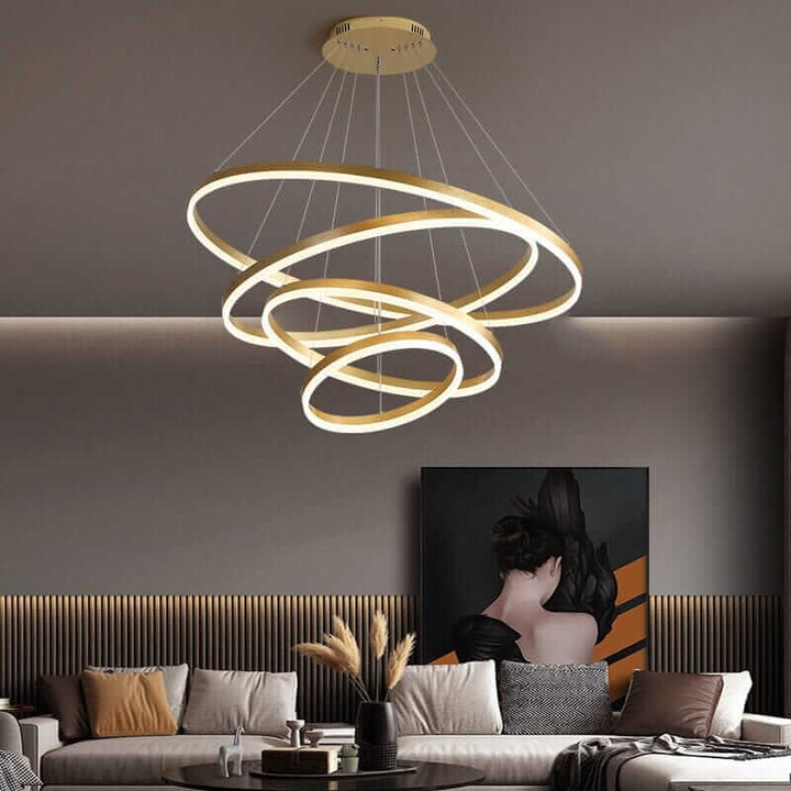 Gold and black chandelier with interconnected rings, illuminating a modern living room with a sophisticated glow.