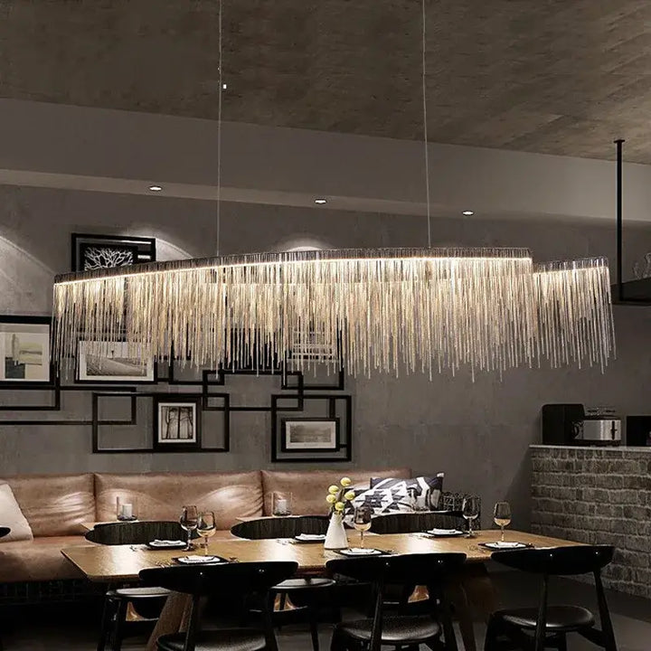 Linear chandelier with tassel design illuminating a modern dining room, enhancing its elegant aesthetics.