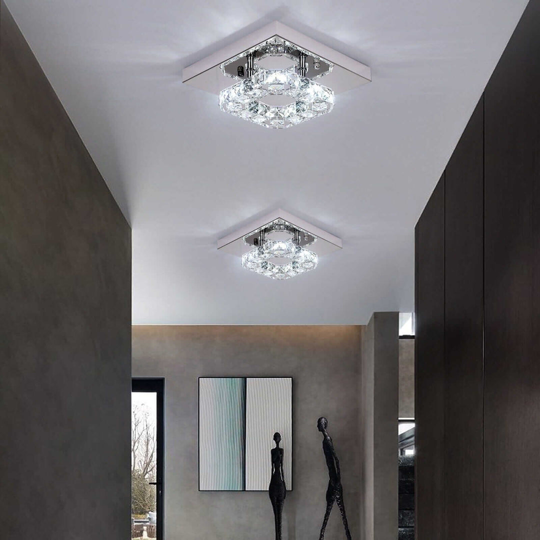 Elegant small crystal chandelier illuminates a modern hallway with minimalistic decor and artistic wall art.