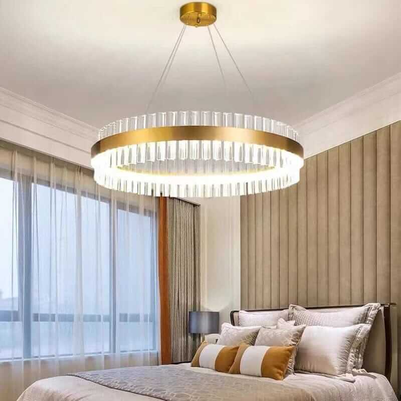 Gold crystal chandelier illuminating a stylish bedroom with elegant decor and natural light.