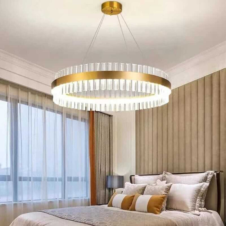 Gold crystal chandelier illuminating a stylish bedroom with elegant decor and natural light.