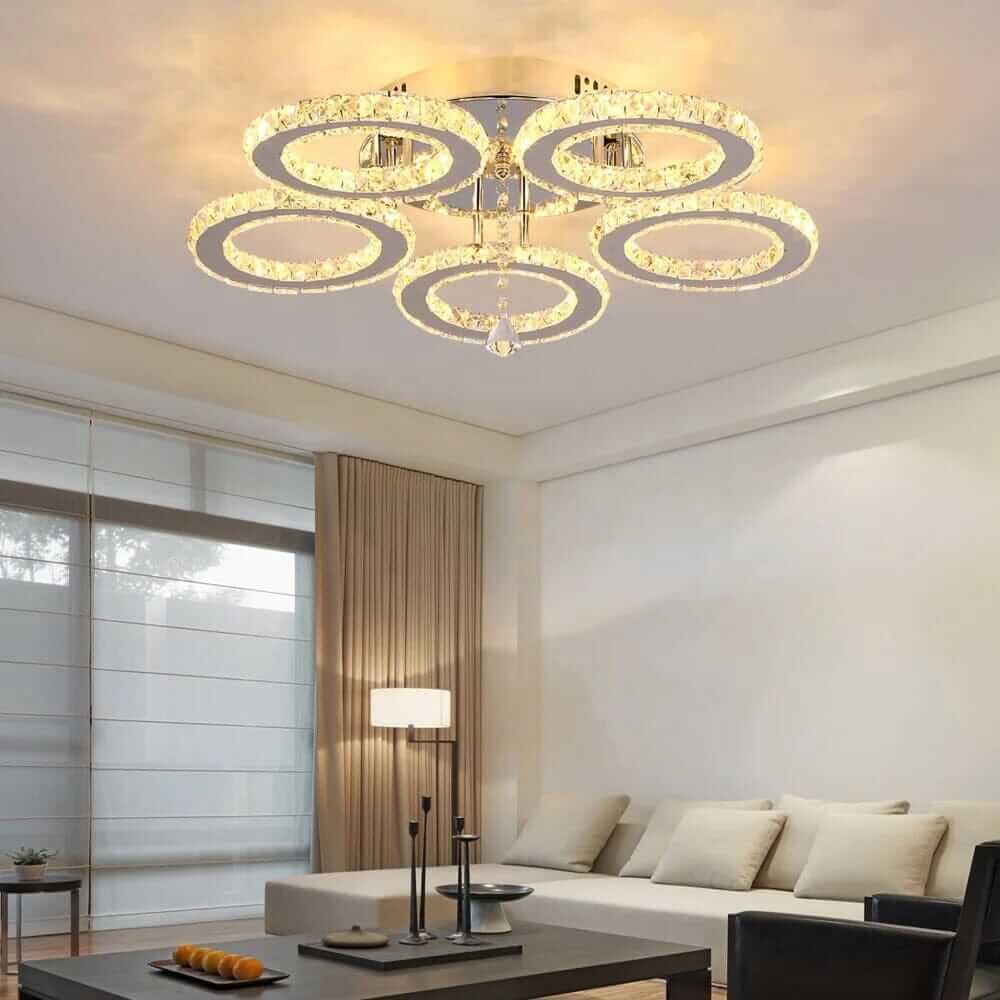 Modern small crystal chandelier with circular tiers illuminating a stylish living room interior.