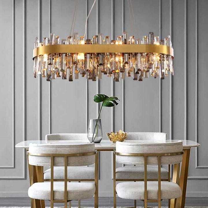 Gold crystal chandelier illuminating a modern dining area with elegant chairs and stylish decor.