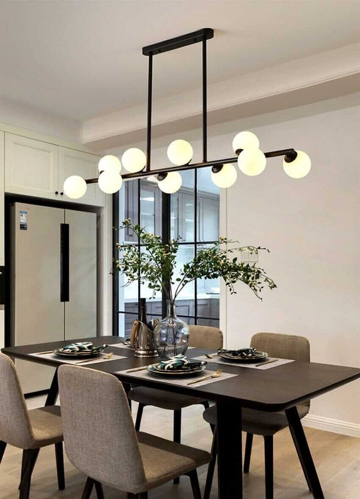 Modern Bubble Chandelier illuminating a stylish dining table with grey chairs and a vase of greenery.