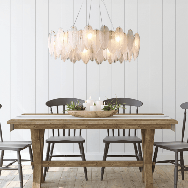 Stylish entryway chandelier featuring leaf-shaped design, illuminating a rustic dining table with wooden chairs.