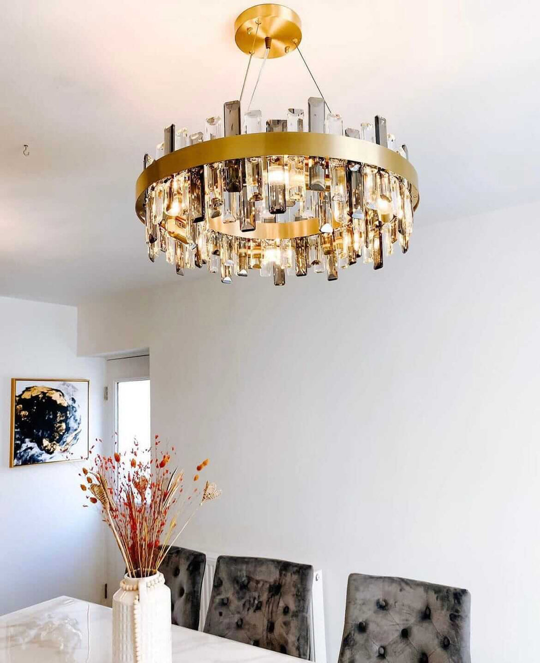 Elegant gold crystal chandelier hanging in modern dining room, enhancing the space with luxurious lighting and design.