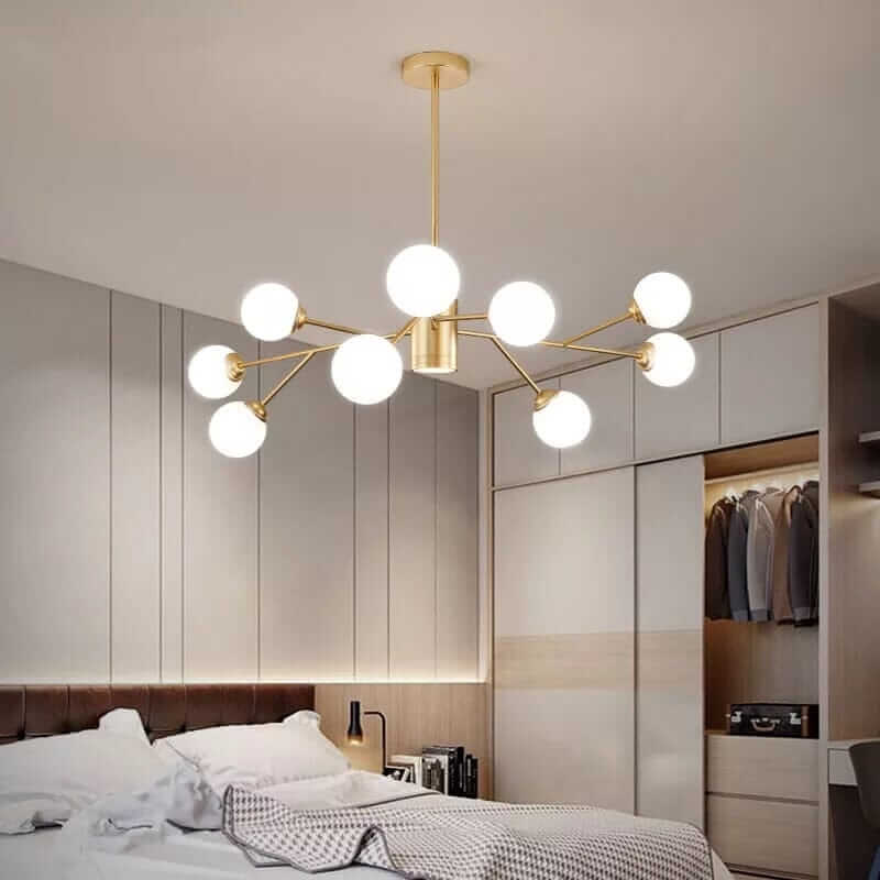 Stylish gold bubble chandelier illuminating a modern bedroom with plush bedding and organized closet.
