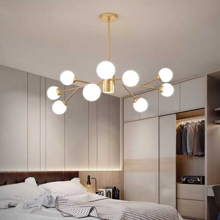 Stylish gold bubble chandelier illuminating a modern bedroom with plush bedding and organized closet.