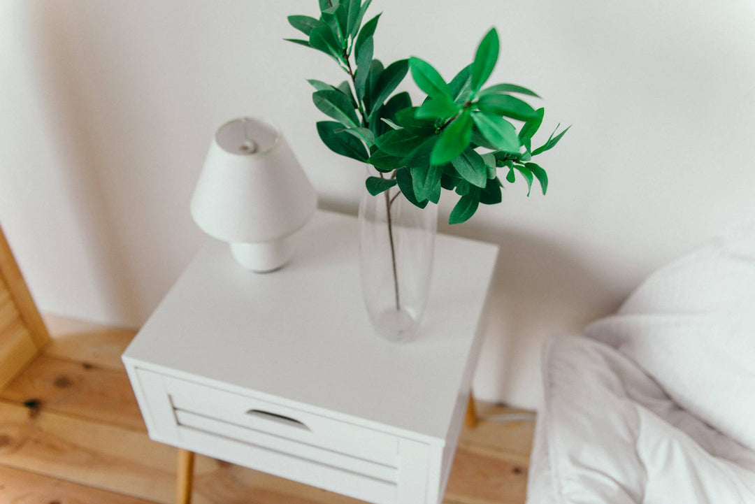 Side Tables with a vase of greens and a lamp on a white side table in a cozy interior.