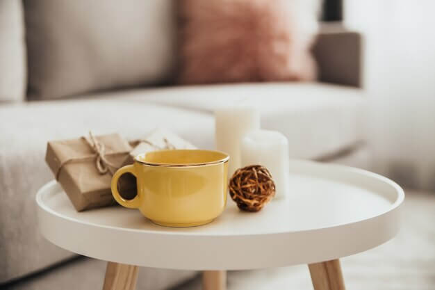Cozy coffee table setup with yellow coffee cup, candles, and decor for stylish coffee tables in small spaces.