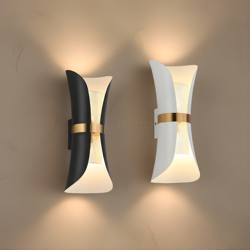 Two modern wall lights with black, white, and gold design on a beige wall.