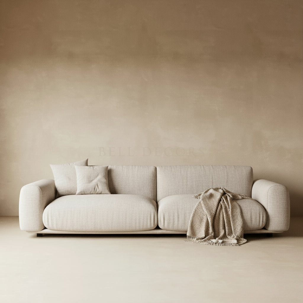 Beige sofa with a blanket and pillows against a beige wall