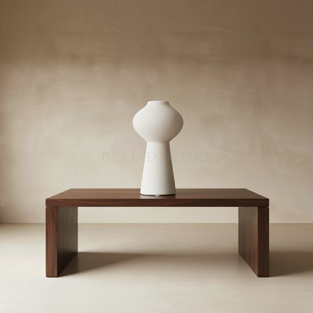 White vase on a wooden table against a beige wall
