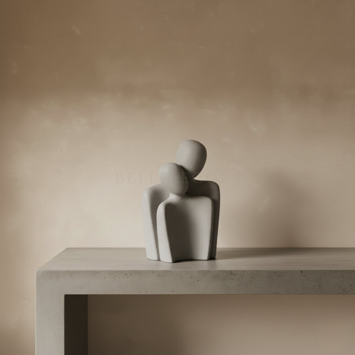 Abstract sculpture of two figures on a concrete surface with a beige background