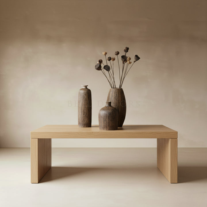 Three wooden vases on a wooden table against a beige wall