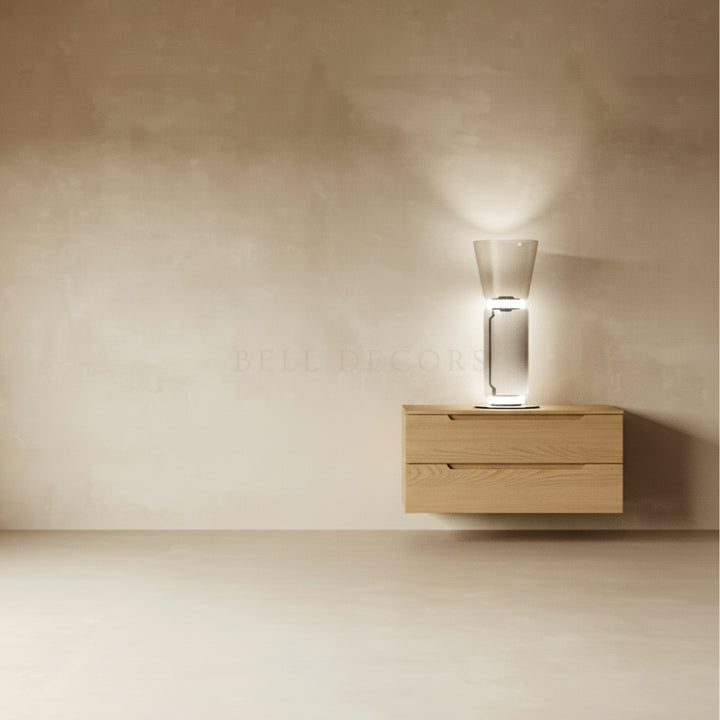 Wooden nightstand with a glass lamp against a beige wall