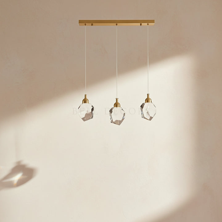 Modern pendant light with three crystal shades on a neutral background