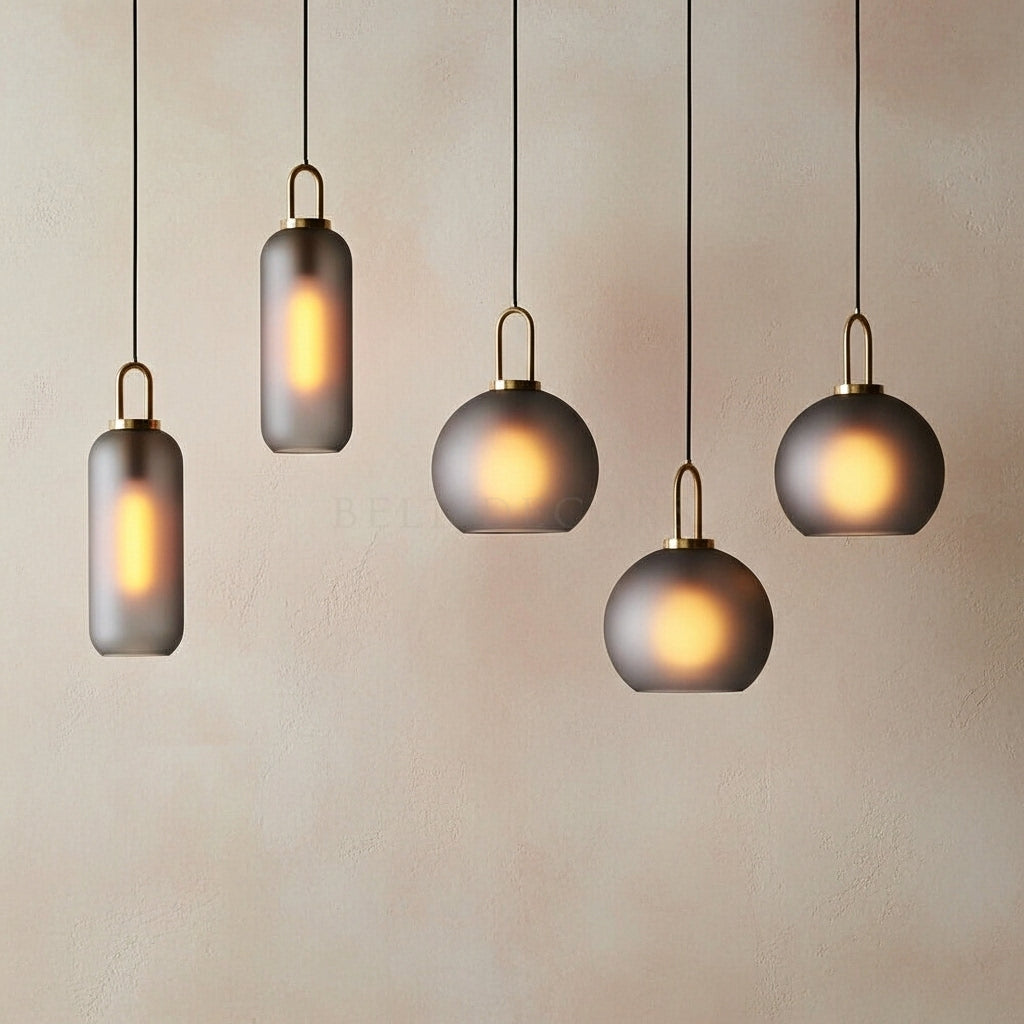 Five modern pendant lights hanging against a plain wall.