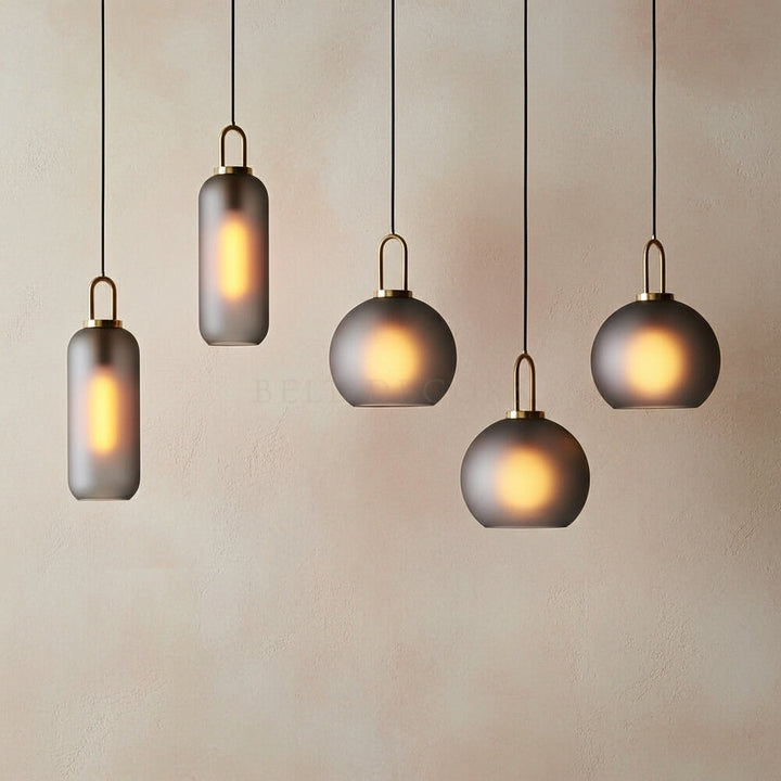 Five modern pendant lights hanging against a plain wall.
