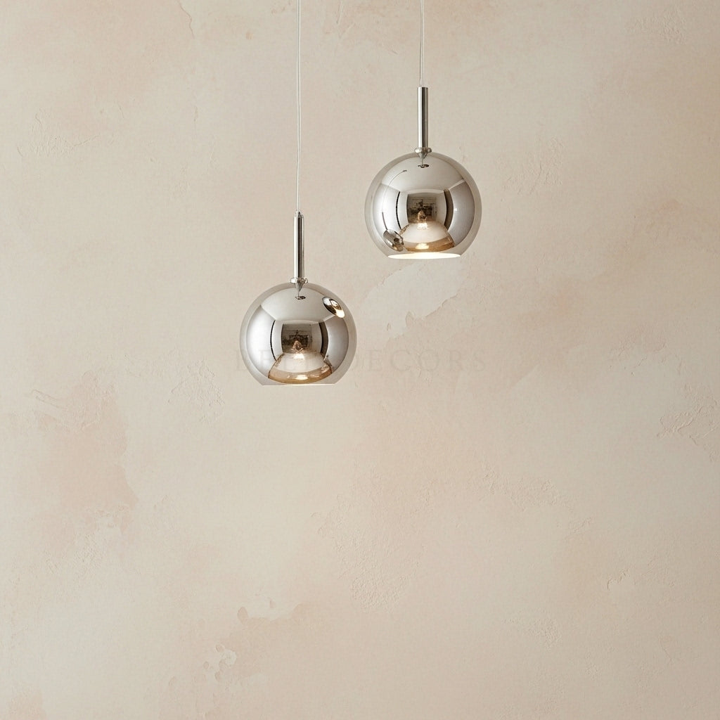 Two silver pendant lights hanging against a beige wall.