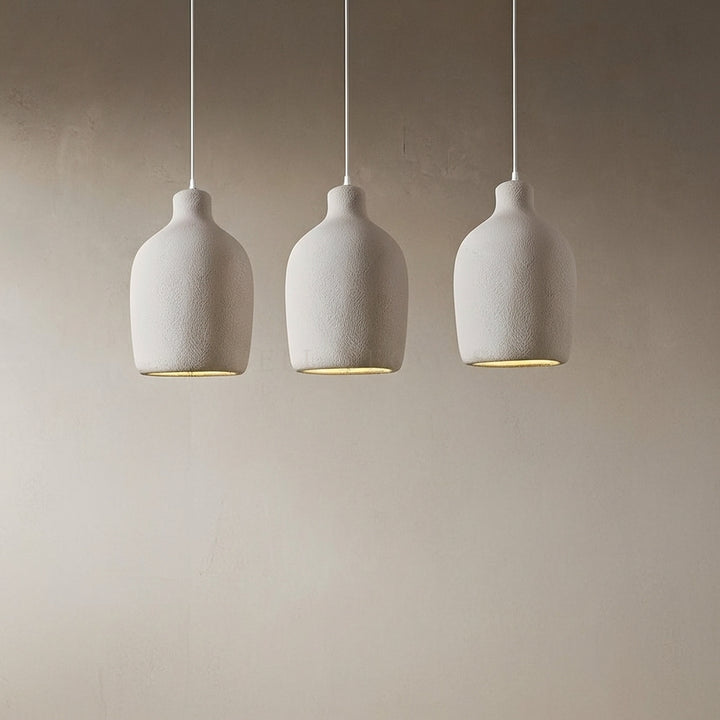 Three white ceramic pendant lights hanging against a beige wall.