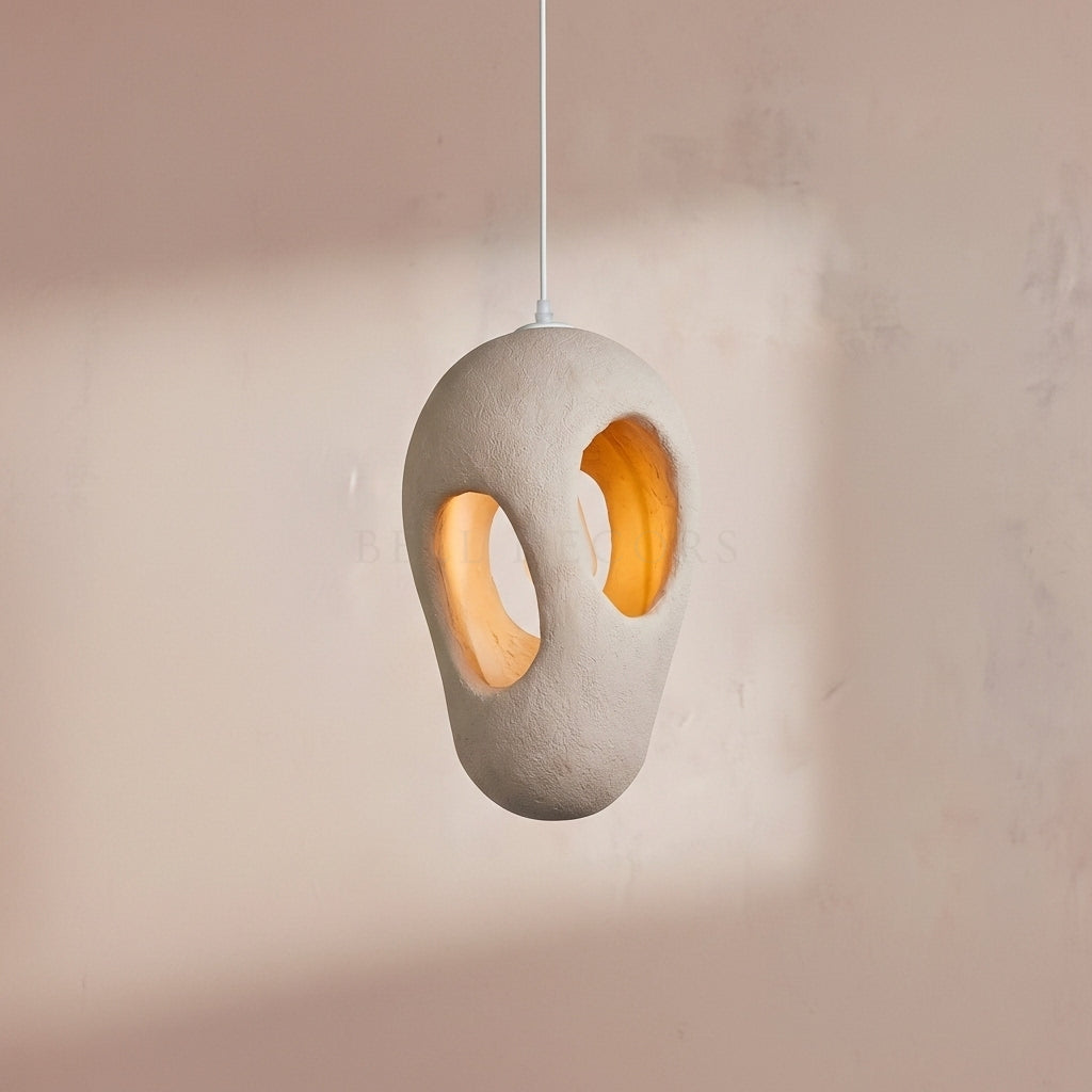 Concrete pendant light with a warm glow on a soft pink background