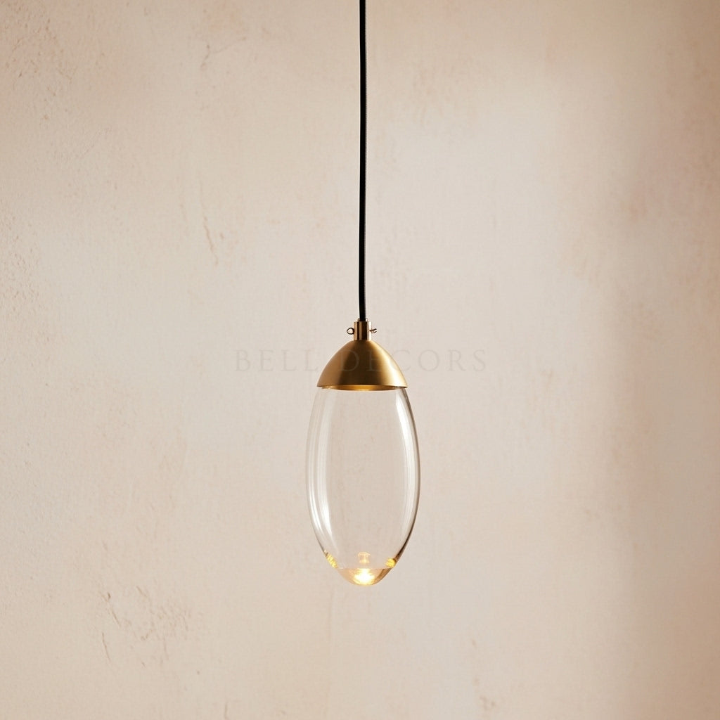 Pendant light with clear glass shade and gold fixture on a beige background