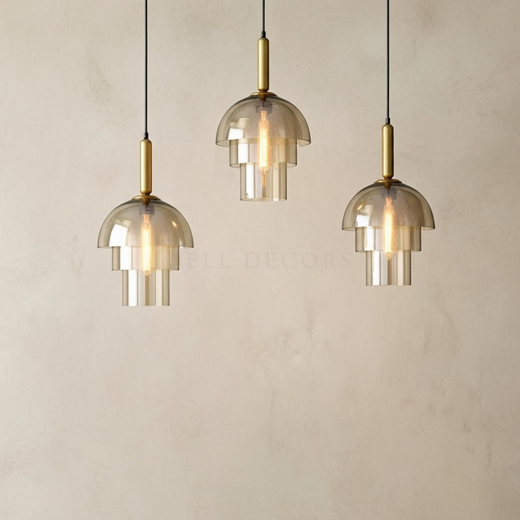 Three modern pendant lights with glass shades and gold accents on a neutral background